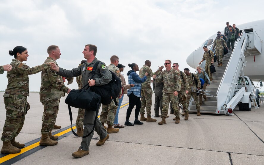 Airmen greet other Airmen as they step off an aircraft.