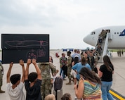 Friends and family greet other Airmen as they step off an aircraft.
