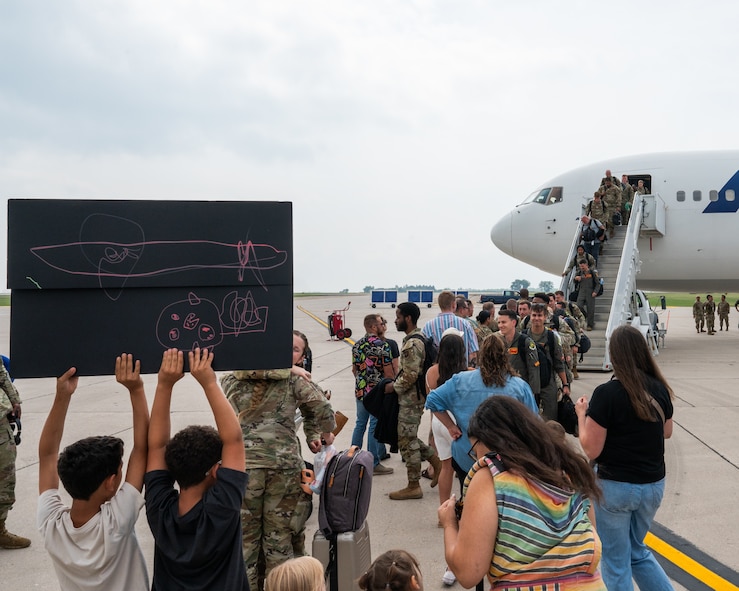 Friends and family greet other Airmen as they step off an aircraft.