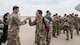 Airmen greet other Airmen as they step off an aircraft.