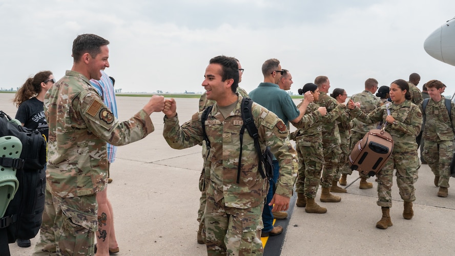 Airmen greet other Airmen as they step off an aircraft.