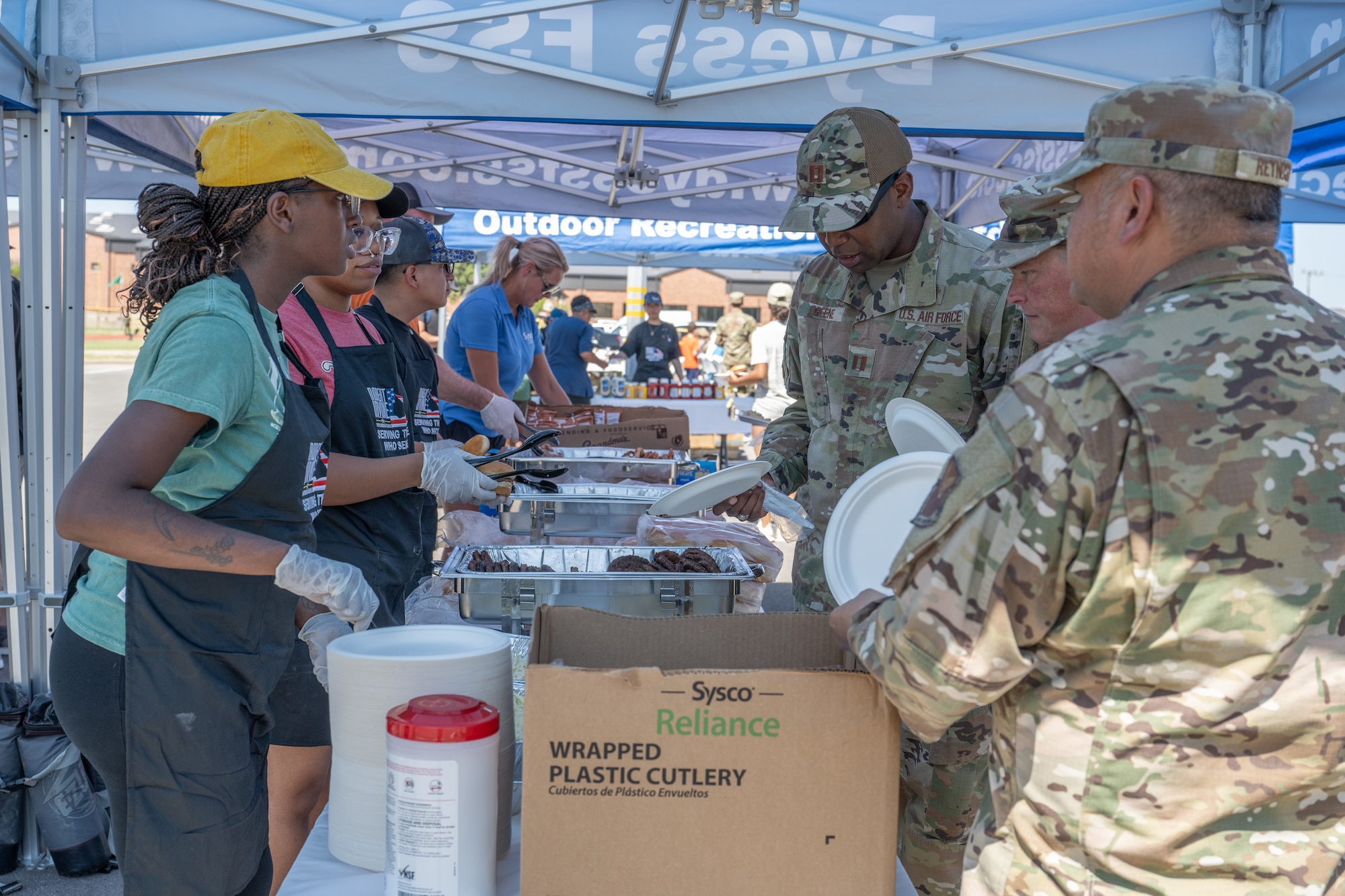 Volunteers serve food to Airmen during the “Breaking Bread with Heroes” event at Dyess Air Force Base, Texas, July 31, 2025. As part of the event, Celebrity Chef Robert Irvine and his foundation provided more than 1,200 meals for Dyess personnel and their families. (U.S. Air Force photo by Airman Caleb Schellenberg)