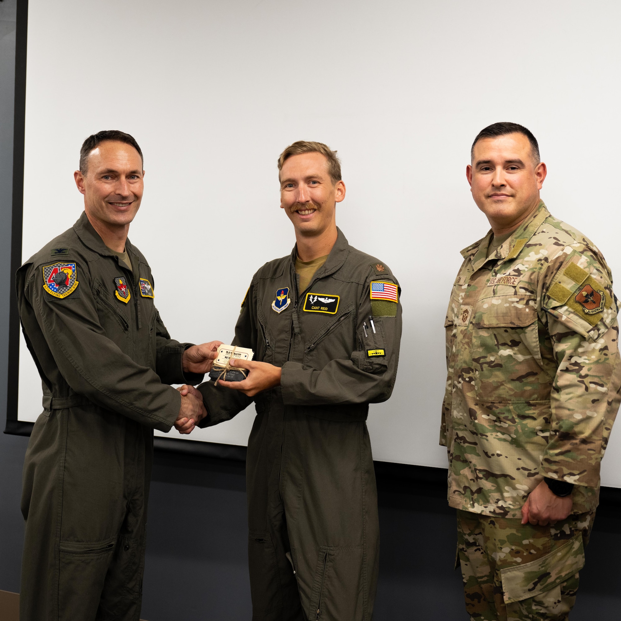 U.S. Air Force Col. Tyler Ellison, 47th Flying Training Wing commander, and Chief Master Sgt. Erik Garza, 47th FTW command chief, present a second quarter award at Laughlin Air Force Base, August 1, 2025. The quarterly awards ceremony honored Airmen and civilians who demonstrated exceptional performance, leadership, and mission impact across the wing. (U.S. Air Force photo by Airman 1st Class Harrison Sullivan)