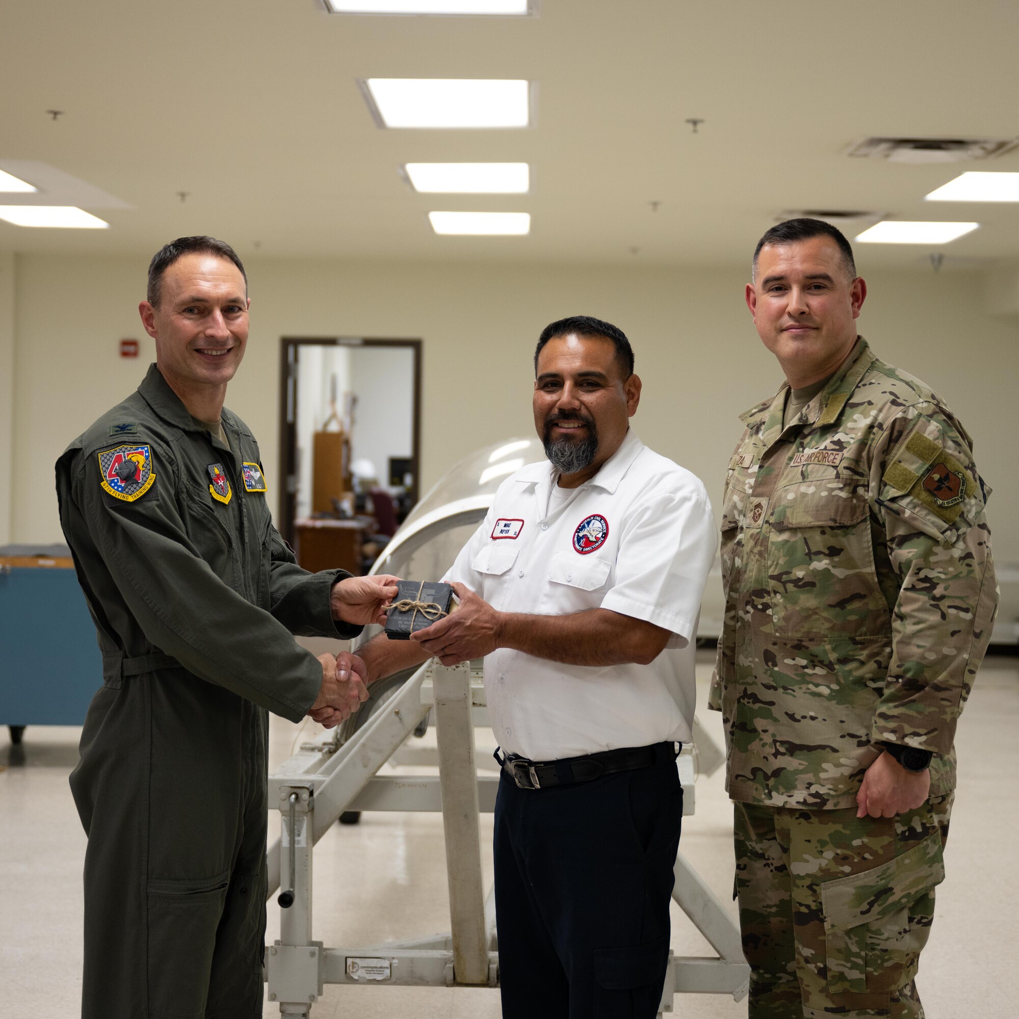 U.S. Air Force Col. Tyler Ellison, 47th Flying Training Wing commander, and Chief Master Sgt. Erik Garza, 47th FTW command chief, present a second quarter award at Laughlin Air Force Base, August 1, 2025. The quarterly awards ceremony honored Airmen and civilians who demonstrated exceptional performance, leadership, and mission impact across the wing. (U.S. Air Force photo by Airman 1st Class Harrison Sullivan)