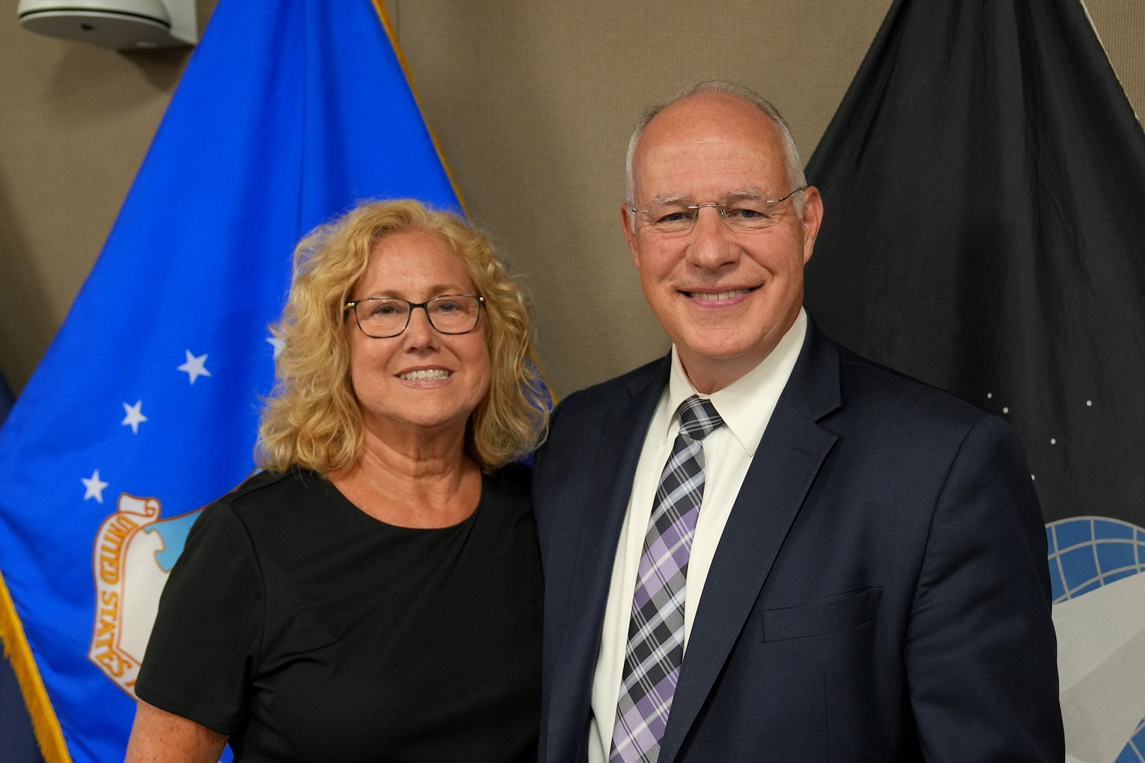 civilian man and woman stand in front of flags