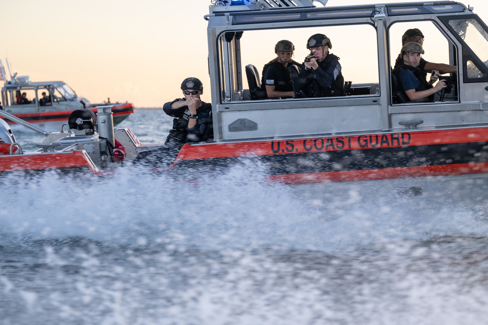 U.S. Coast Guard members aboard a Response Boat–Medium maintain visual security and aim training weapons during a Non-Compliant Vessel Pursuit exercise near Homestead, Florida, June 16, 2025.