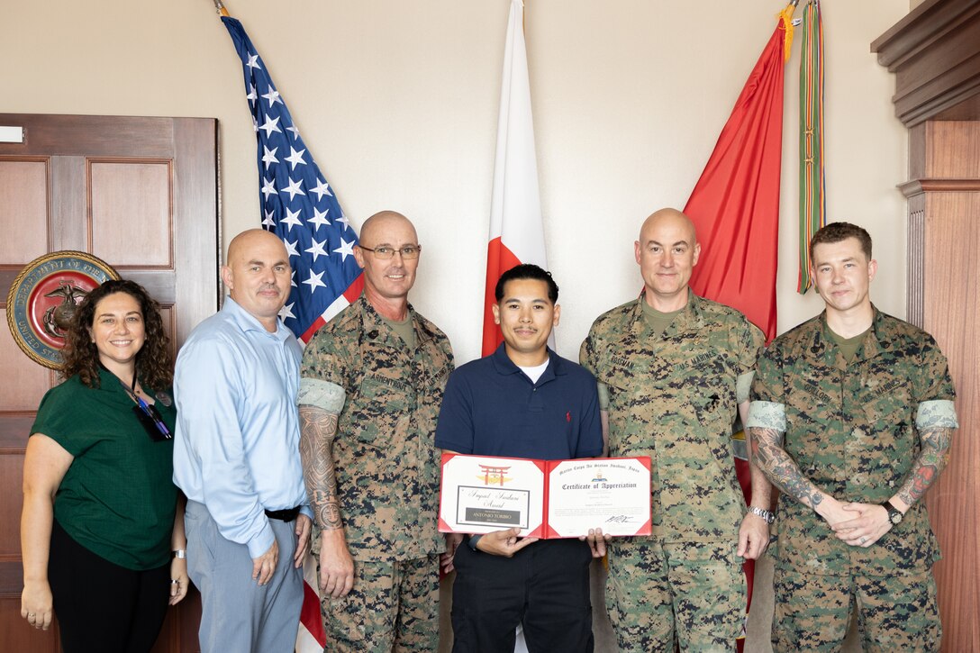 Sgt. Maj. Jody Armentrout, right, sergeant major of Marine Corps Air Station Iwakuni, reads the Impact Iwakuni award to Antonio Toribio, a sales representative with the Marine Corps Exchange, during the July 2025 Impact Iwakuni award ceremony at MCAS Iwakuni, Japan, July 29, 2025. Toribio was nominated for recognition after receiving numerous positive Interactive Customer Evaluations (ICE) from members of MCAS Iwakuni, and his hard work and excellent customer service have had a positive impact on the installation. (U.S. Marine Corps photo by Cpl. Brian Long)