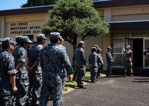 A U.S. military member greets Japan Air Self-Defense force members at the entrance of a building.