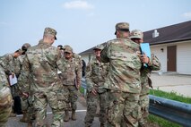 U.S. Air Force Col. William J. Watkins, 22nd Air Task Force (ATF) commander, left, and Chief Master Sgt. Erick Lizarraga, 22nd ATF command chief, right, welcome arriving participants at Fort Custer, Michigan, Aug. 3, 2025.