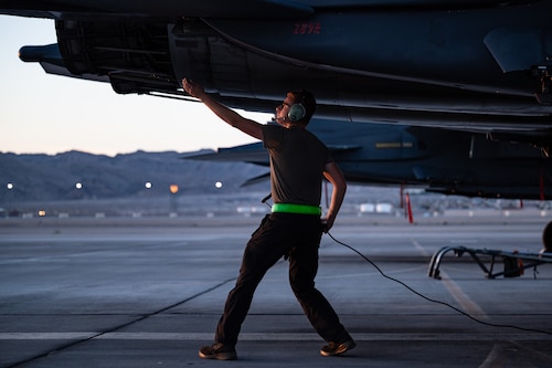 Airmen walks under plane.
