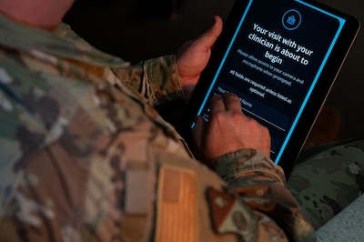 Service member clicks on tablet. Screen reads: "Your visit with your clinician is about to begin."