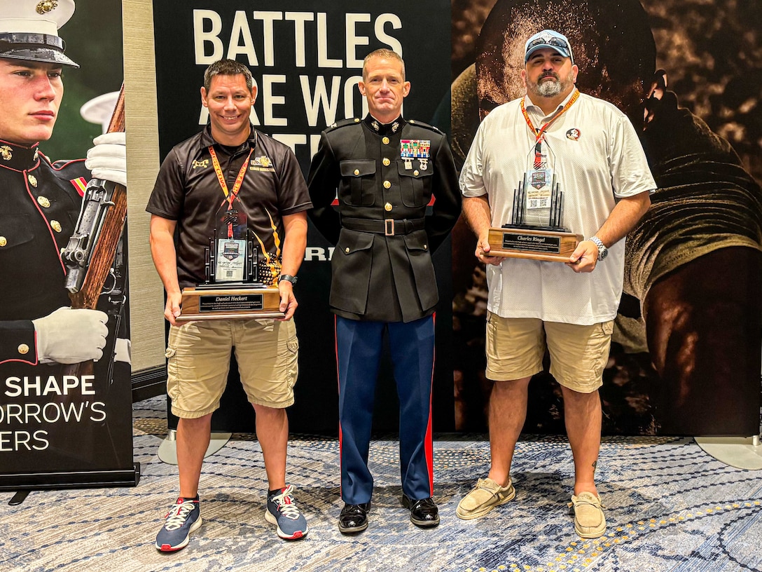 U.S. Marine Corps Col. Joseph Galvin, right, a staff judge advocate for Headquarters Marine Forces Command, awards wrestling coaches Charles Ringel from Leon High School in Tallahassee, Florida, center, and Daniel Heckert from North Allegheny High School in Wexford, Pennsylvania, left, during the Battle Won Awards at the National Wrestling Coaches Association Convention in Ponte Vedra, Florida August 2, 2025. Throughout the event, MCRC engaged with wrestling coaches to highlight shared values and characteristics that make wrestlers exceptional candidates for service in the Marine Corps. (Courtesy photo by Marine Corps Recruiting Command)