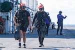 Naval Aircrewman (Helicopter) 3rd Class Zachary Santos, left, from Brockton, Massachusetts, and Naval Aircrewman (Helicopter) 2nd Class Ethan Kubat, right, from Lincoln, Illinois, assigned to Helicopter Sea Combat Squadron (HSC) 25 walk across the flight deck of the forward-deployed amphibious assault ship USS America (LHA 6), while conducting flight operations in the Philippine Sea, Feb. 27. America, lead ship of the America Amphibious Ready Group, is operating in the U.S. 7th Fleet area of operations. U.S. 7th Fleet is the U.S. Navy’s largest forward-deployed numbered fleet, and routinely interacts and operates with allies and partners in preserving a free and open Indo-Pacific region.