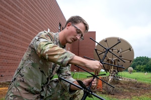 U.S. Air Force Senior Airman Verlin K. Harper, 263rd Combat Communications Squadron radio-frequency transmission systems operator, sets up an antenna for tactical satellite communication at the New London Air National Guard base, N.C., August 1, 2025.