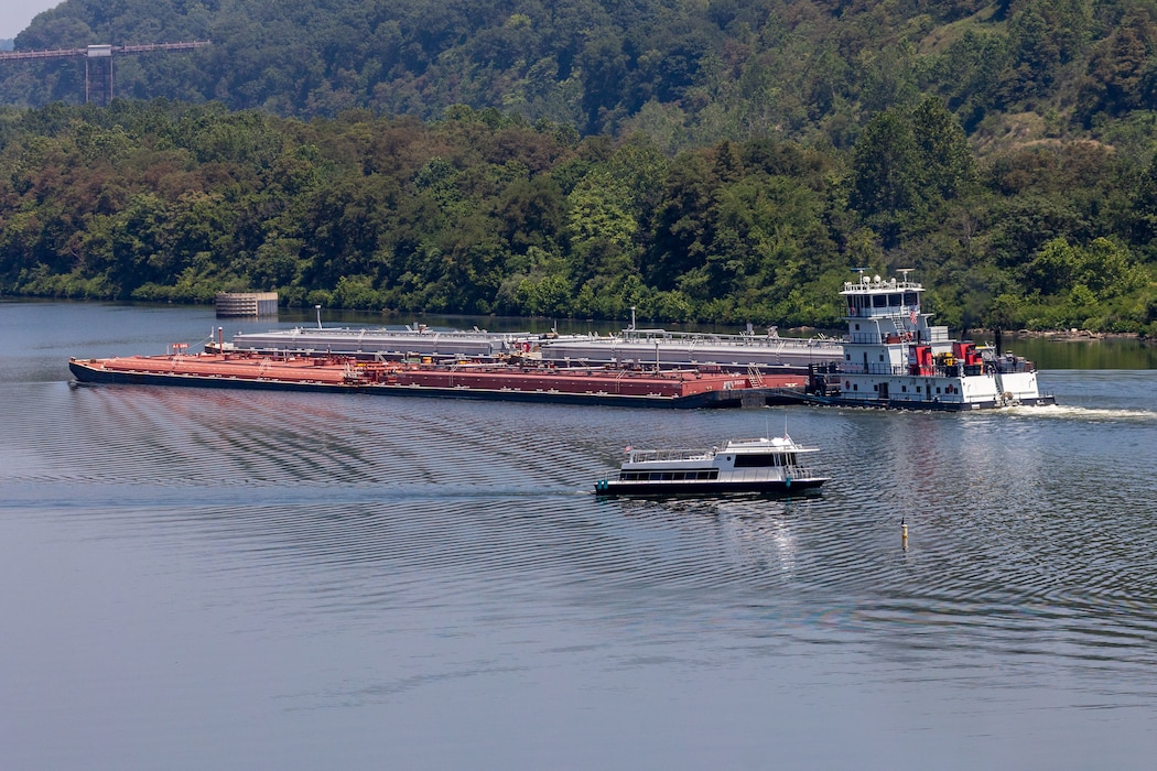 A small boat passes by a barge on a river.
