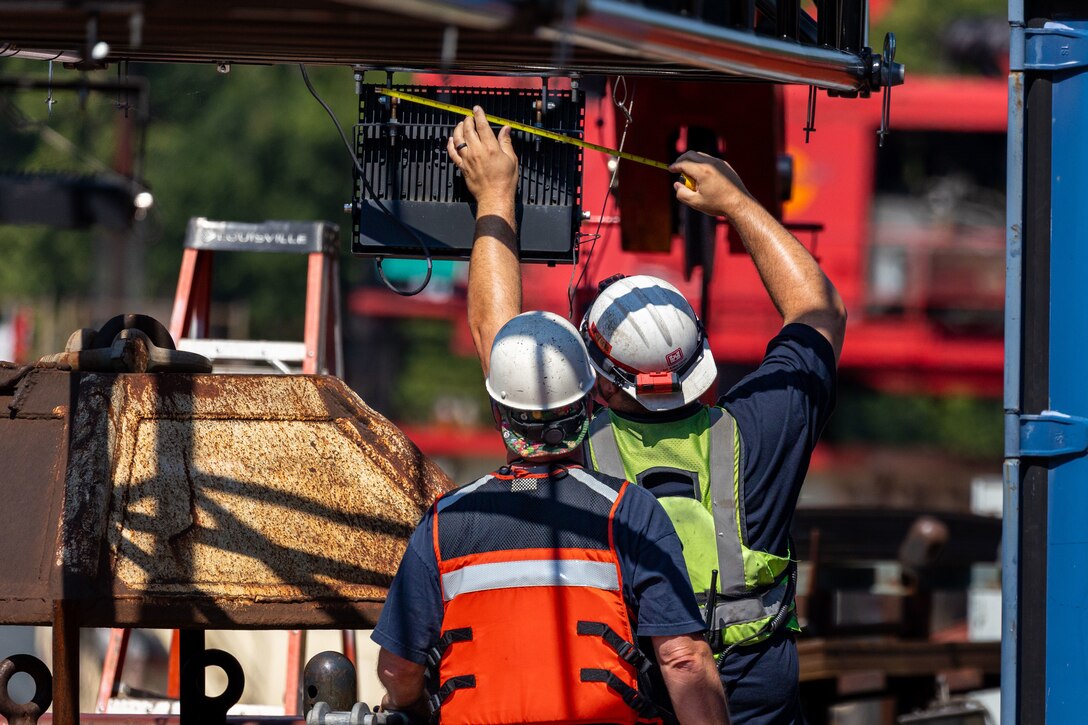 Construction crews adjust machinery on a working barge at a river lock.