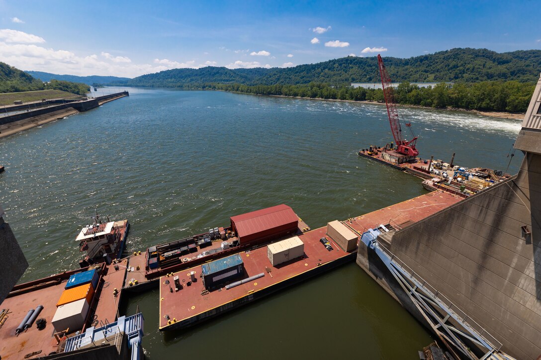 Construction equipment sits on a working barge at a river lock.