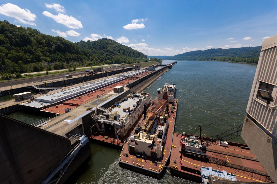 Construction equipment sits on a working barge at a river lock.