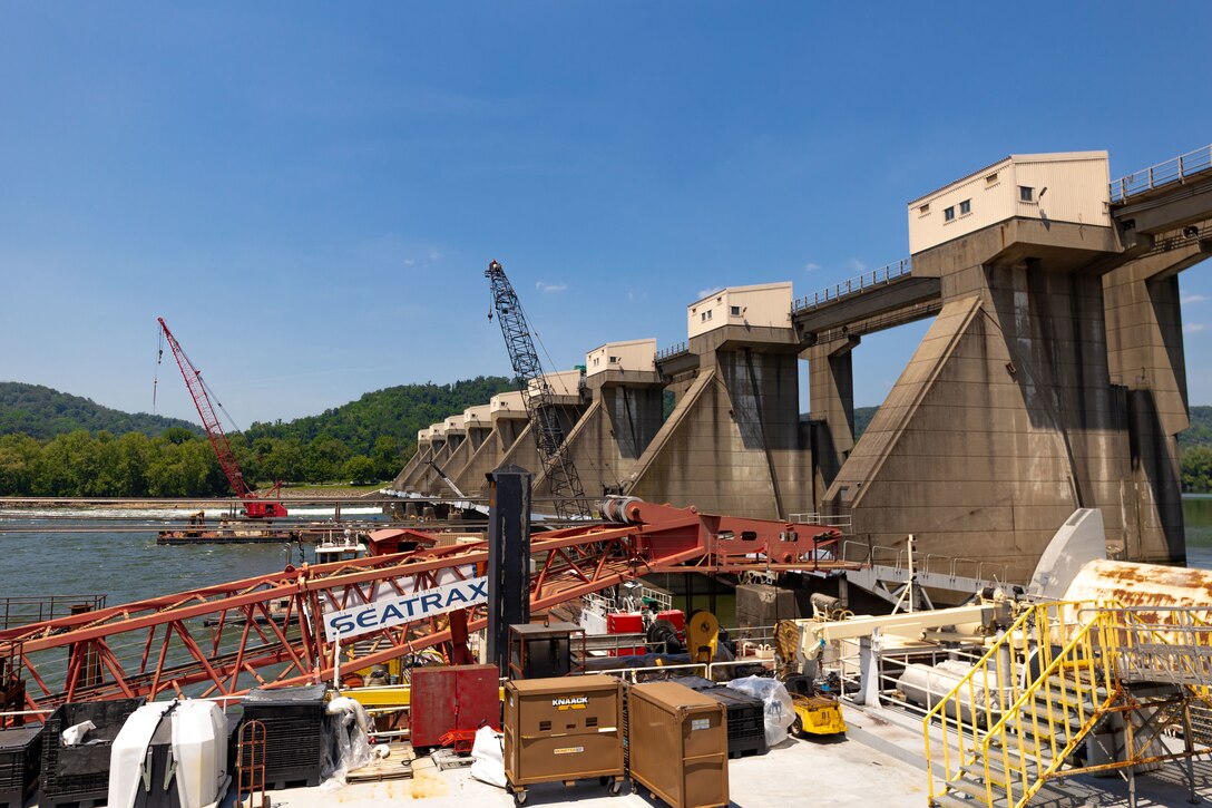 Construction equipment sits on a working barge at a river lock.