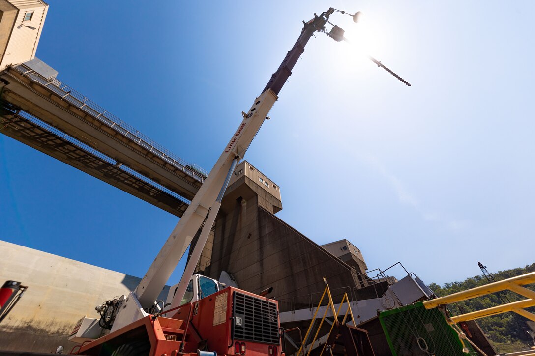 A crane sits on a working barge at a river lock.
