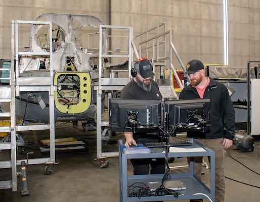 Chris Smith, left, airframes mechanic, and Todd Baker, right, H-1 production supervisor, access the electronic work order (EWO) system at the Fleet Readiness Center East (FRCE) detachment onboard Marine Corps Air Station Cherry Point in Jacksonville, North Carolina.