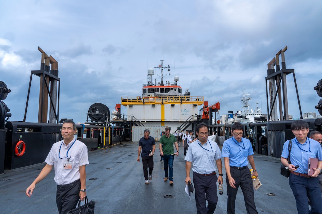 Distinguished visitors explore the Stern Landing Vessel, a modified oil-rig industry off-shore support vessel, in order to better understand its capabilities, Oct. 30, 2024 at Naha Military Port, Okinawa, Japan. The SLV, named the HOS Resolution, is a 267-foot converted offshore support vessel capable of providing 6,000 square feet of usable deck space that has been modified to beach and offload using a stern ramp. The Marine Corps Warfighting Laboratory contracted the SLV to explore maneuver and sustainment options for Stand-In Forces to inform the development of the Medium Landing Ship. (U.S. Marine Corps photo by Kevin Ray J. Salvador)