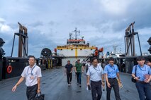 Distinguished visitors explore the Stern Landing Vessel, a modified oil-rig industry off-shore support vessel, in order to better understand its capabilities, Oct. 30, 2024 at Naha Military Port, Okinawa, Japan. The SLV, named the HOS Resolution, is a 267-foot converted offshore support vessel capable of providing 6,000 square feet of usable deck space that has been modified to beach and offload using a stern ramp. The Marine Corps Warfighting Laboratory contracted the SLV to explore maneuver and sustainment options for Stand-In Forces to inform the development of the Medium Landing Ship. (U.S. Marine Corps photo by Kevin Ray J. Salvador)
