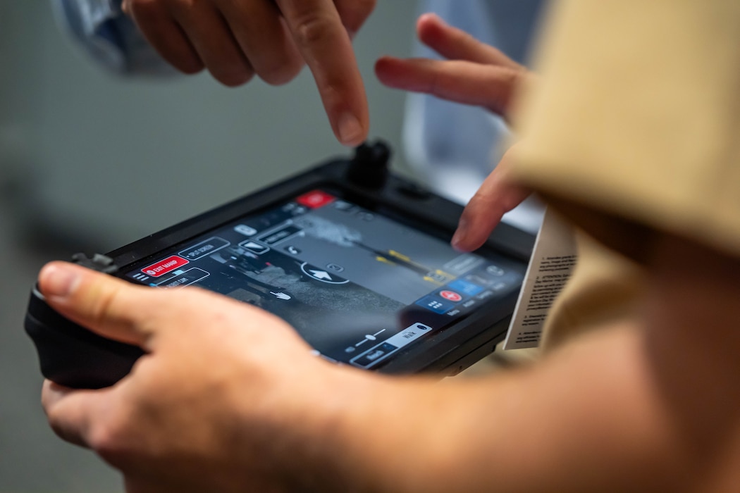 From left, Mr. John Kelley, Marine Corps Warfighting Laboratory, helps U.S. Marine Corps Cpl. Hayden Hedinger, operate a robot dog using a remote controller, during Modern Day Marine at the Walter E. Washington Convention Center, Washington D.C., April 30th, 2025. Modern Day Marine is a military exposition exclusively organized for the Marine Corps to showcase the newest technology and warfighting innovations from amphibious assault vehicles to drones and more. (U.S. Marine Corps photo by Connor Taggart)