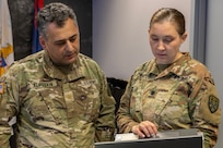 Maj. Cihan Alptekin, U.S. Army Finance and Comptroller School proponency officer, and Lt. Col. Pampuch-Borden, U.S. Army Financial Management Command reserve component finance and comptroller senior advisor, discuss operations during a staff exercise at the Maj. Gen. Emmett J. Bean Federal Center in Indianapolis Oct. 31, 2024. USAFMCOM hosted the exercise to increase its operational capabilities through the four phases of the conflict continuum, reduce its inefficiencies in battle tasks, and clearly identify financial management roles, responsibilities and authorities. (U.S. Army photo by Mark R. W. Orders-Woempner)