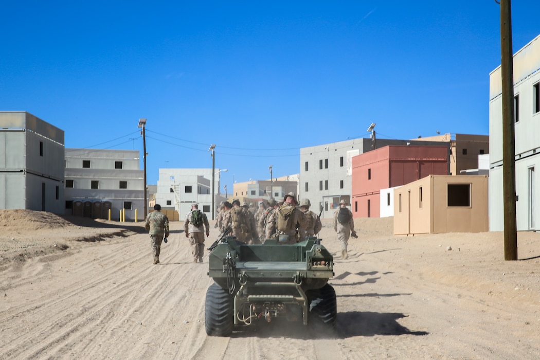 A Mission Master unmanned ground vehicle follows U.S. Marines with 3rd Battalion, 4th Marine Regiment (REIN) to the Military Operations in Urban Terrain facility through Range 220 at Marine Corps Air-Ground Combat Center, Twentynine Palms, California, Oct. 17, 2023. The Mission Master by Rheinmetall was designed for the purpose of increasing logistical flexibility in the field. (U.S. Marine Corps photo by Kevin Ray J. Salvador)
