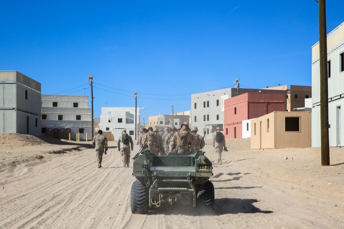 A Mission Master unmanned ground vehicle follows U.S. Marines with 3rd Battalion, 4th Marine Regiment (REIN) to the Military Operations in Urban Terrain facility through Range 220 at Marine Corps Air-Ground Combat Center, Twentynine Palms, California, Oct. 17, 2023. The Mission Master by Rheinmetall was designed for the purpose of increasing logistical flexibility in the field. (U.S. Marine Corps photo by Kevin Ray J. Salvador)