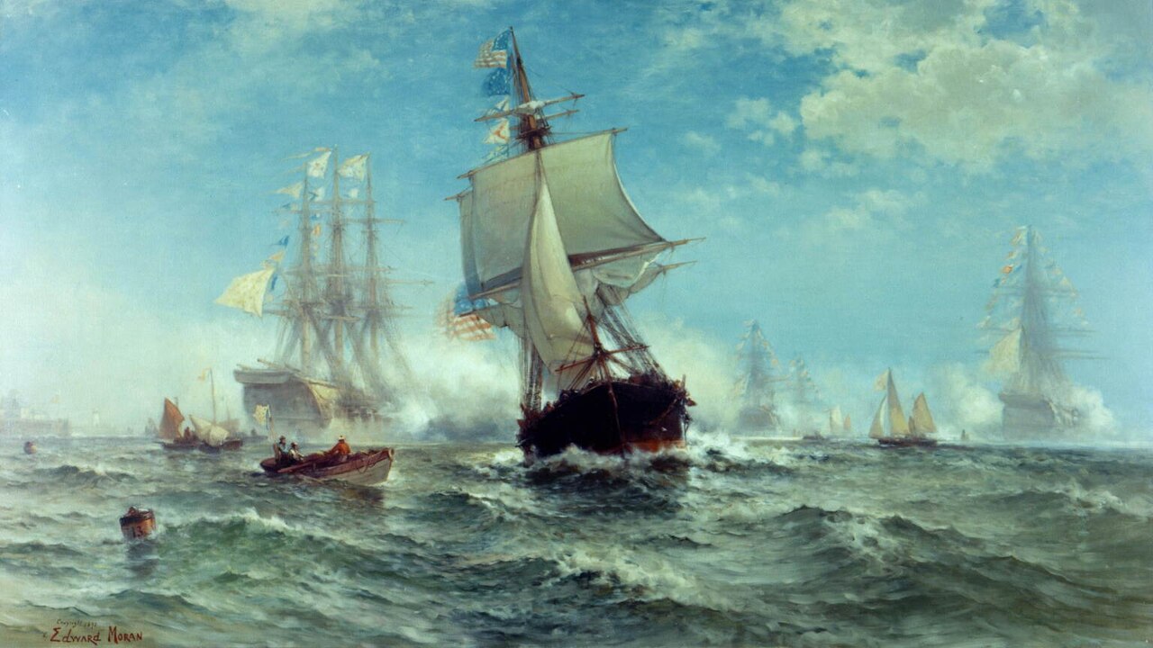 Many sailing ships and a small boat move through the ocean waves under a blue sky with puffy white clouds.