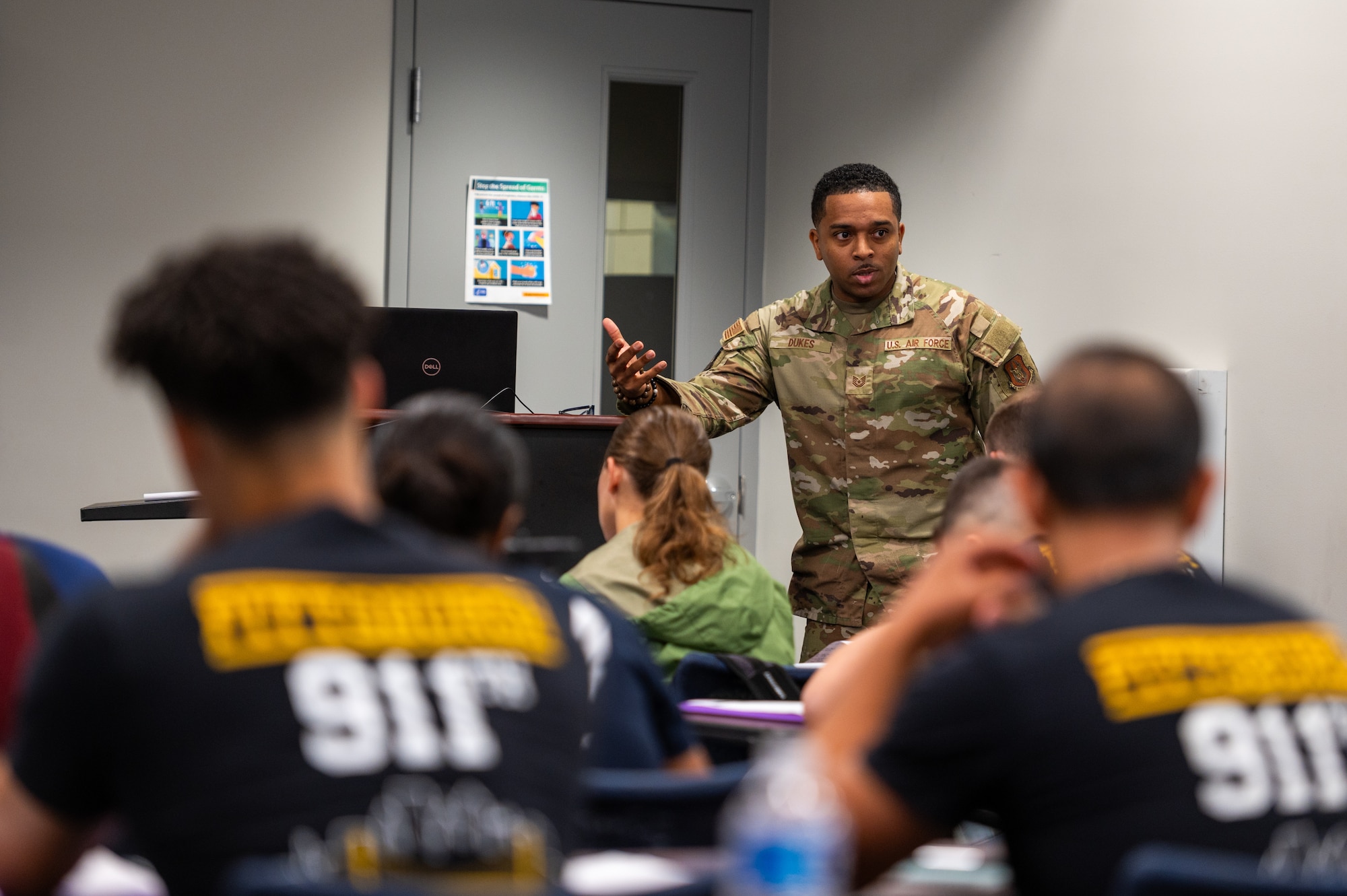 an African American male in a camouflage uniform teaches in front of a class of new recruits.