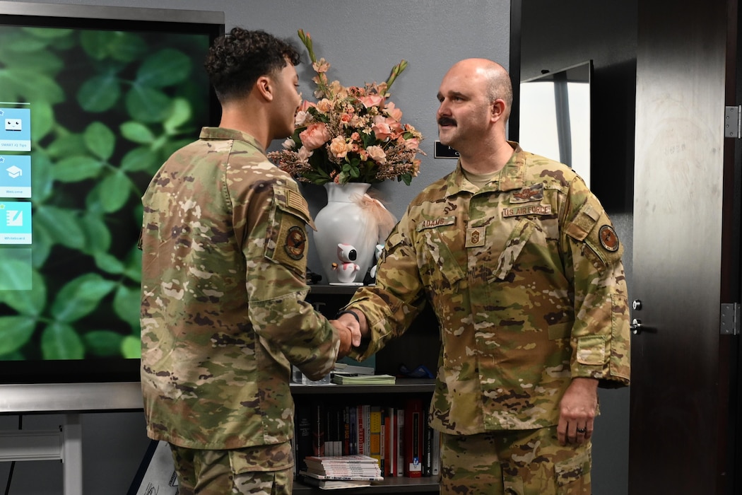 U.S. Air Force Airman 1st Class Desmond Davis, 97th Contracting Flight contracting specialist, shakes hands with Chief Master Sgt. Jonny Adams, 97th Air Mobility Wing command chief, at Altus Air Force Base, Oklahoma, Aug 1, 2025. Davis was given a coin as recognition for his Airman of the Month accomplishment. (U.S. Air Force Airman 1st Class Lauren Torres)
