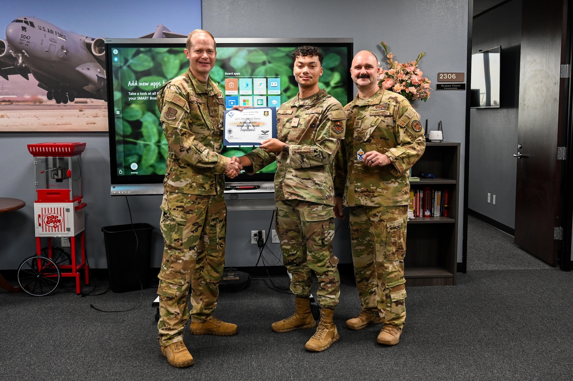 U.S. Air Force Col. Richard Kind, 97th Air Mobility Wing (AMW) commander, and Chief Master Sgt. Jonny Adams, 97th AMW command chief, hands an award to Airman 1st Class Desmond Davis, 97th Contracting Flight contracting specialist, at Altus Air Force Base, Oklahoma, Aug 1, 2025. Davis was awarded Airman of the Month for June, a title given to outstanding Airmen. (U.S. Air Force photo by Airman 1st Class Lauren Torres)