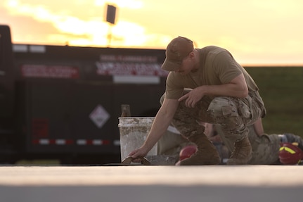 Tech. Sgt. Alan Bauman, the structures NCO in charge with the 157th Civil Engineer Squadron, smooths concrete as the sun rises at the 201st Regional Training Site, Fort Indiantown Gap, Pennsylvania, July 30, 2025. The team of engineers constructed a new runway from the ground up and worked as a team alongside Airmen from the 219th CES, Montana Air National Guard. (U.S. Air National Guard photo by Tech. Sgt. Victoria Nelson)