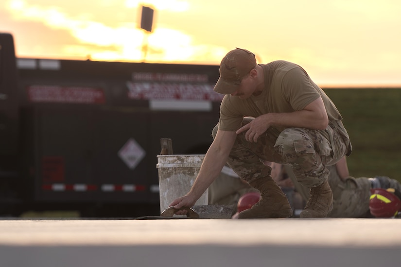 Tech. Sgt. Alan Bauman, the structures NCO in charge with the 157th Civil Engineer Squadron, smooths concrete as the sun rises at the 201st Regional Training Site, Fort Indiantown Gap, Pennsylvania, July 30, 2025. The team of engineers constructed a new runway from the ground up and worked as a team alongside Airmen from the 219th CES, Montana Air National Guard. (U.S. Air National Guard photo by Tech. Sgt. Victoria Nelson)