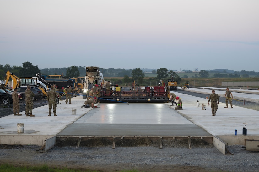 Airmen from the 157th Civil Engineer Squadron Prime Base Engineer Emergency Force and the 219th Civil Engineer Squadron pour 250 cubic yards of concrete at the 201st Regional Training Site, Fort Indiantown Gap, Pennsylvania, July 30, 2025. The large-scale concrete pour showcased joint efforts between New Hampshire and Montana Air National Guard engineers, reinforcing critical skills in airfield construction and multi-unit coordination. (U.S. Air National Guard photo by Tech. Sgt. Victoria Nelson)