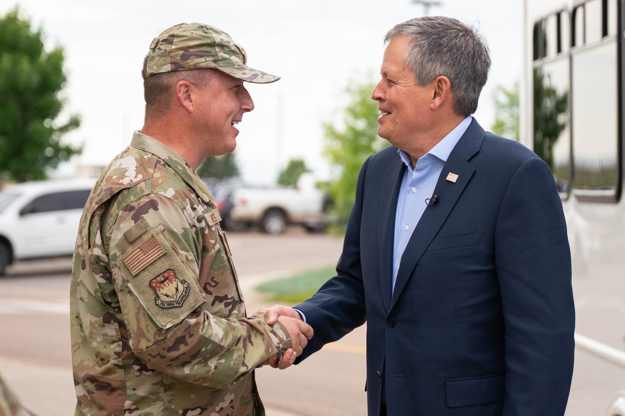 A man in uniform shakes hands with a man in civilian attire.