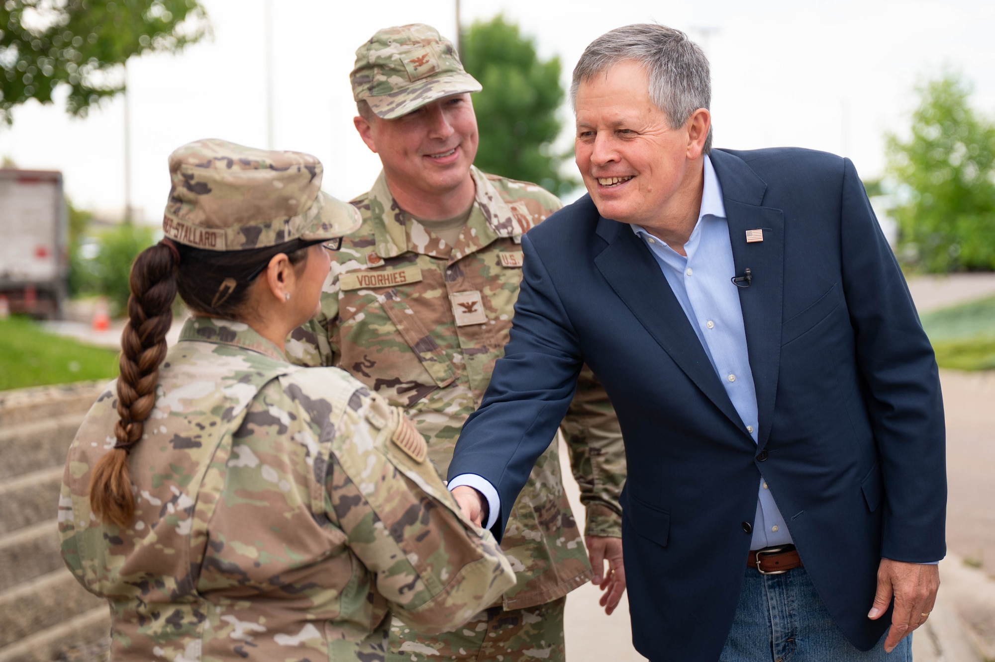 A man in civilian attire shakes hands with a woman in uniform.
