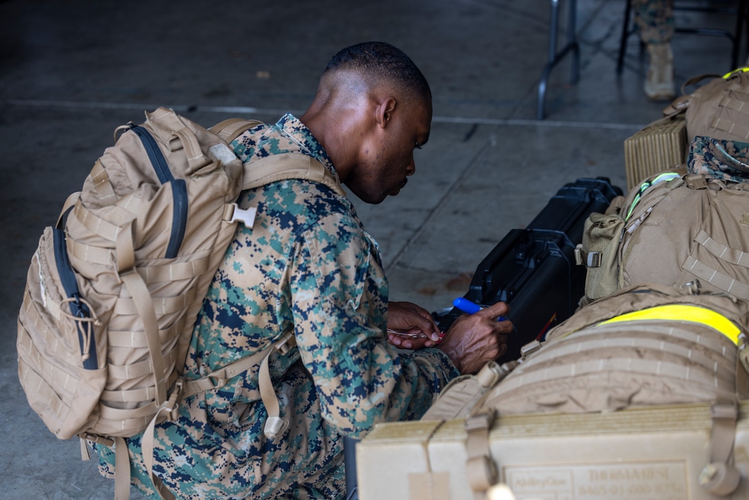 U.S. Marine Corps Capt. Stephen Price puts a tag on his Pelican rifle case during an Alert Contingency Marine Air Ground Task Force (ACM) drill on Camp Courtney, Okinawa, Japan, July 15, 2025. The ACM exercise is a simulated crisis response drill that must be executed within 24 hours to prepare Marines to mitigate emergencies, provide humanitarian aid, or counter threats to U.S. national interests within the Indo-Pacific region. Price, a native of Georgia, is a logistics officer with 3D Marine Expeditionary Brigade. (U.S. Marine Corps photo by Lance Cpl. Jeffrey Pruett)