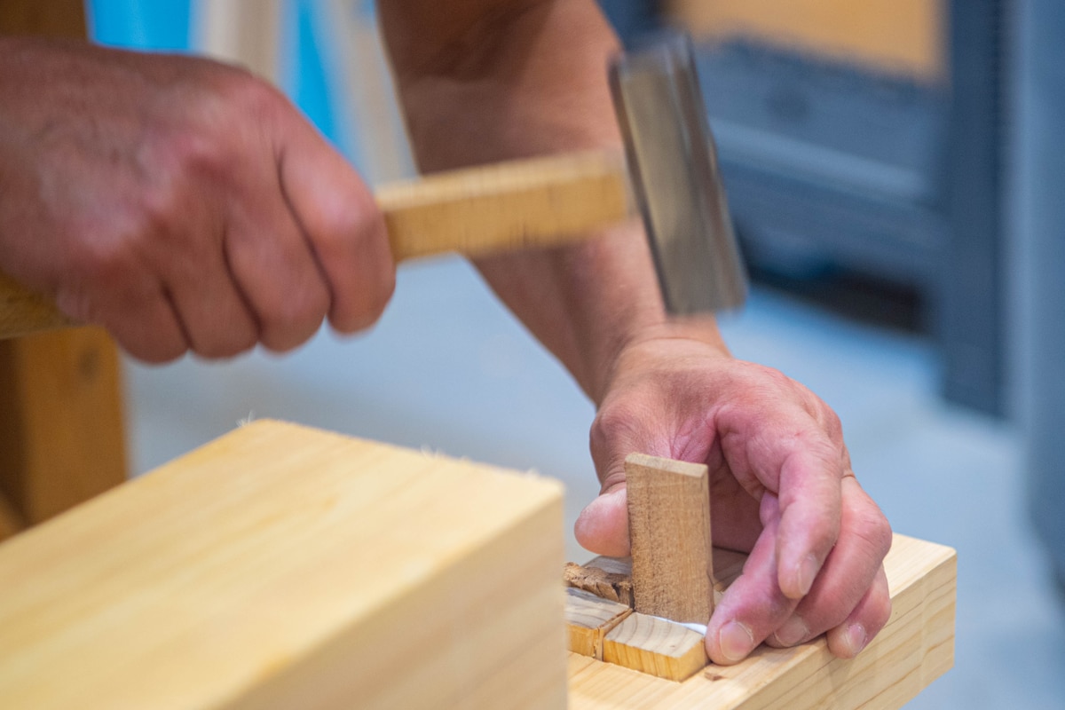 A man hammers wood into a sawhorse.