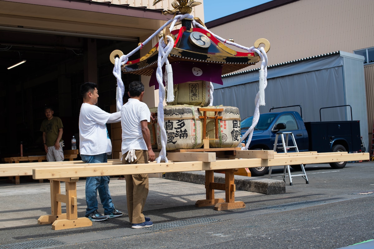 A man fastens a Tori gate to a mikoshi.