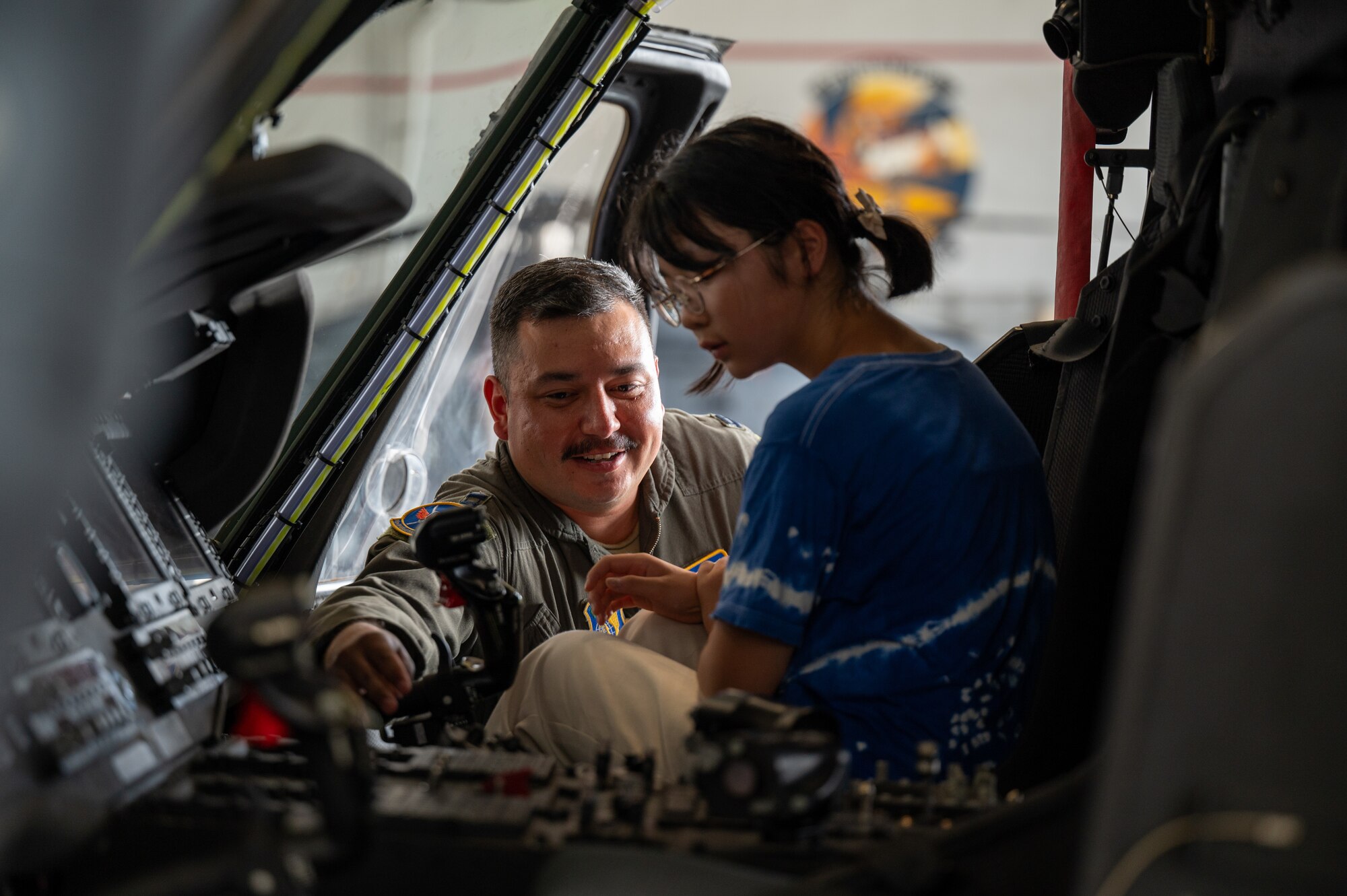 A 33rd Rescue Squadron helicopter pilot teaches an Achi-Mura student the HH-60W Jolly Green II's flight controls