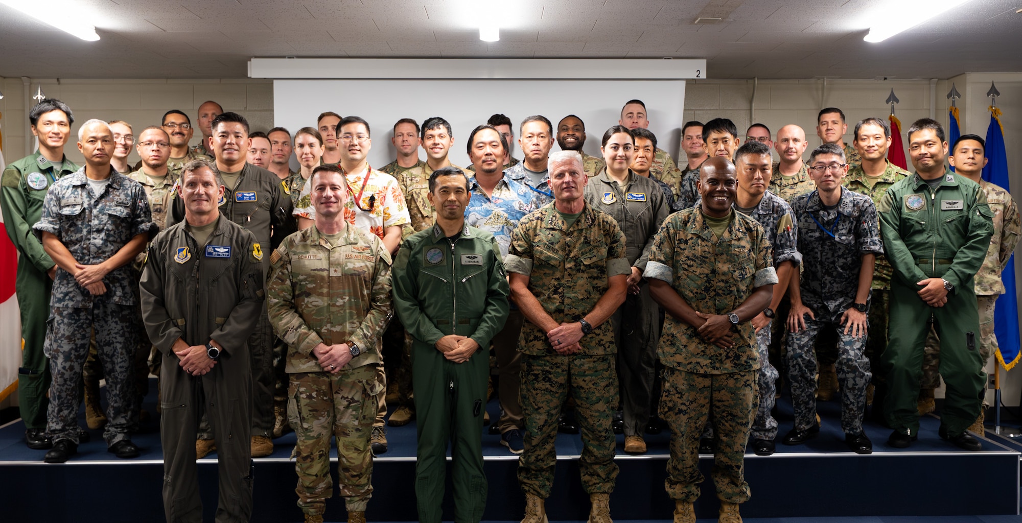 U.S. Air Force, U.S. Marine Corps and Japan Air Self-Defense Force members pose for a photo during the Bilateral Defense of Okinawa Working Group outbrief at Kadena Air Base, Japan, August 1, 2025.