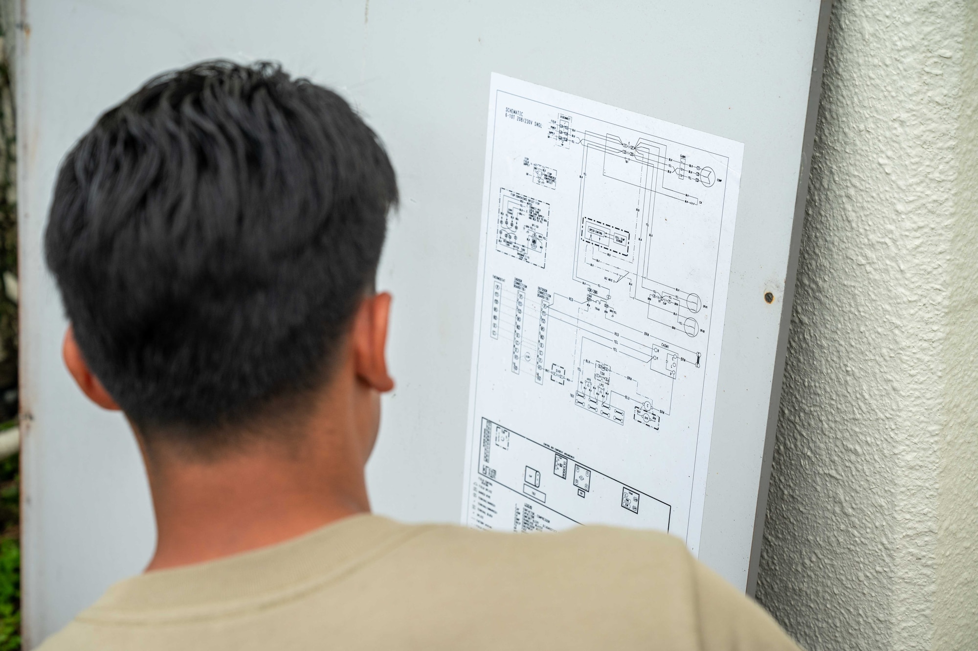 A 718th CES Airman examines an AC unit schematic.