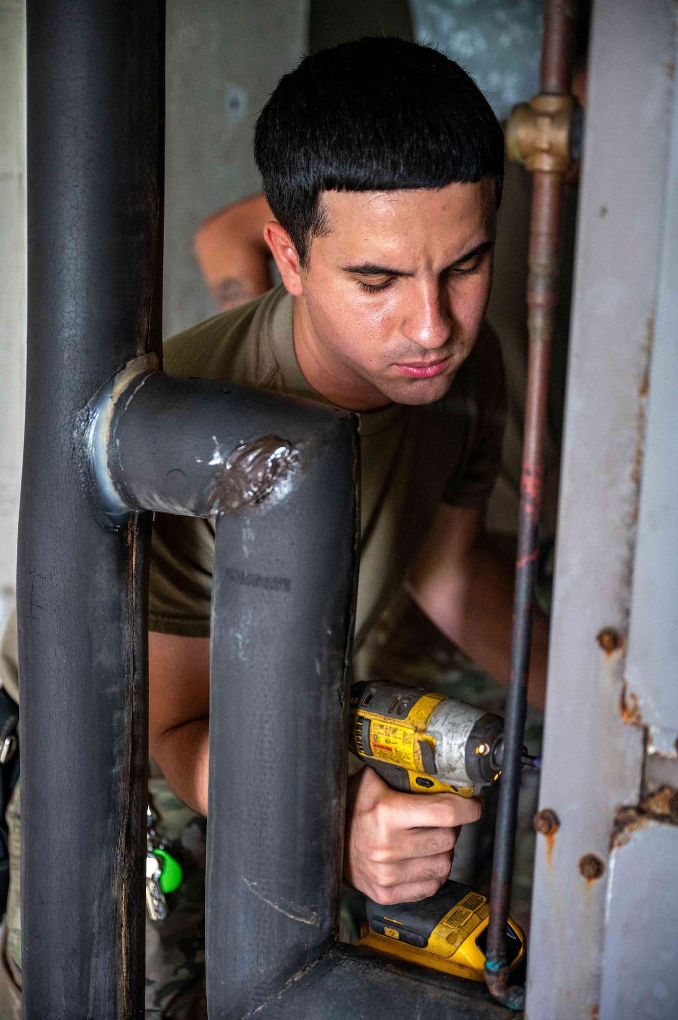 A 718th CES Airman screws a panel back in place with a screw gun.