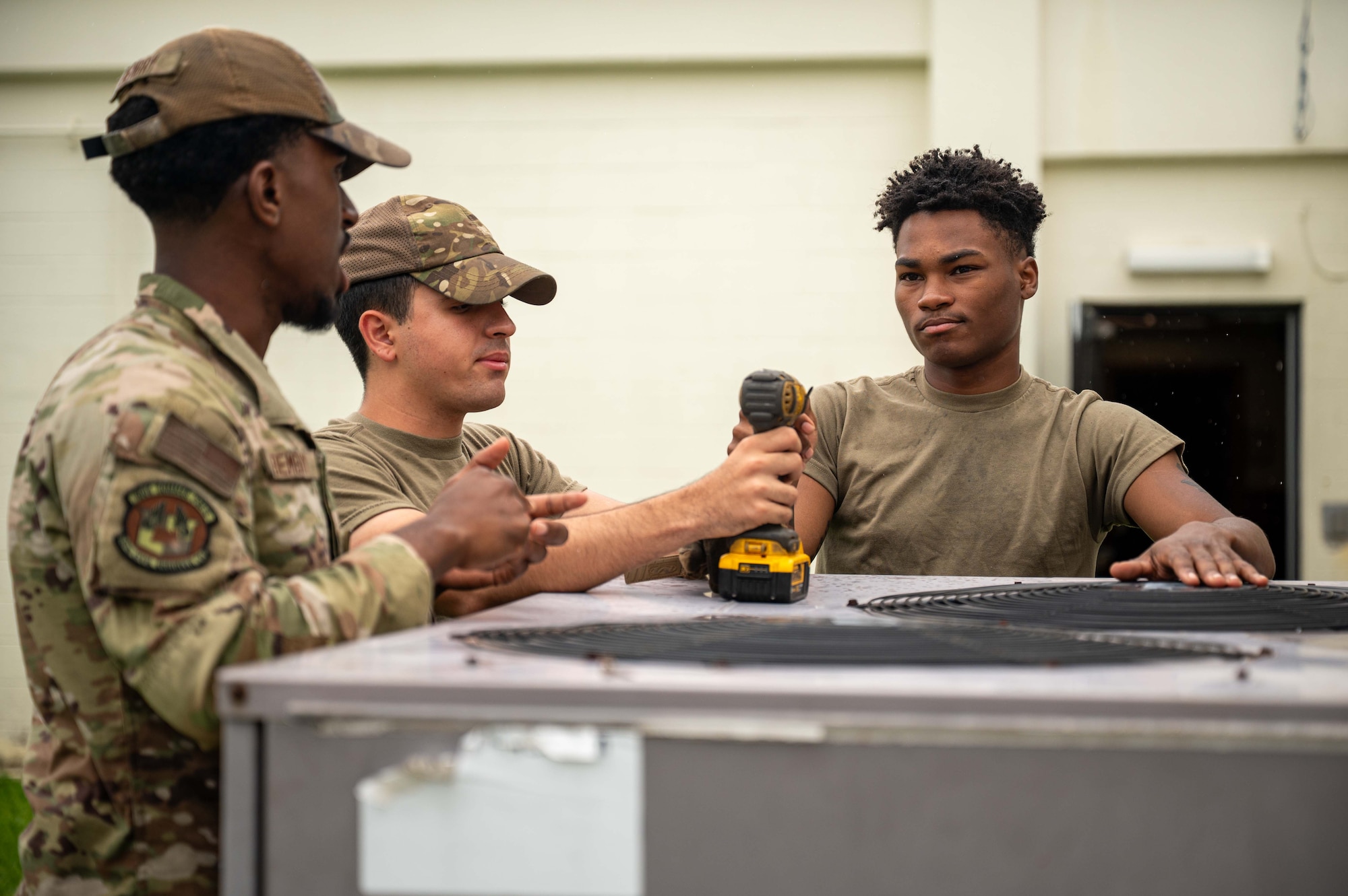 718th CES Airmen conduct an AC unit assessment by conversing.