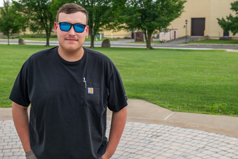 A man wearing sunglasses poses for a photo outside.