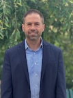 A man in a suit poses for a photo outside.